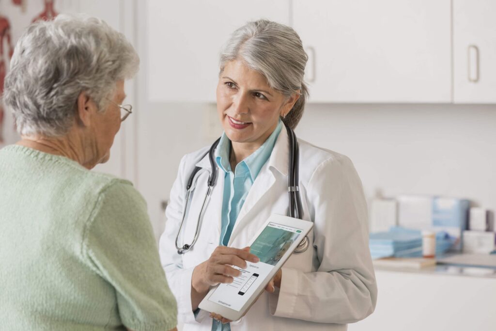 Caucasian doctor and patient using digital tablet in office